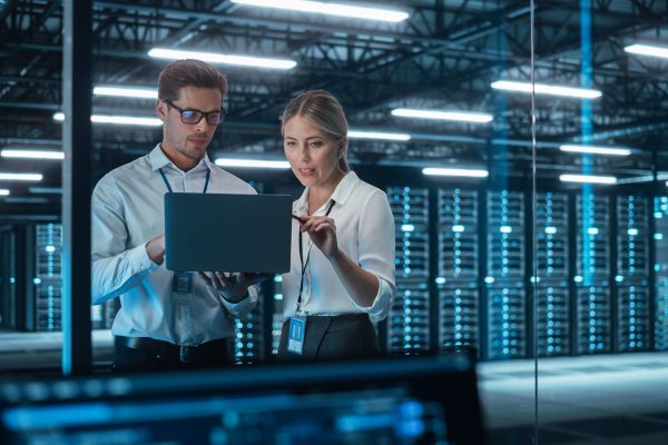 Male CEO Discusses Problem Solving with Female Partner in Office, They Brainstorming while Look on a Laptop. Smart Businesspeople Working in Finance. Specialists Work in Team Concept